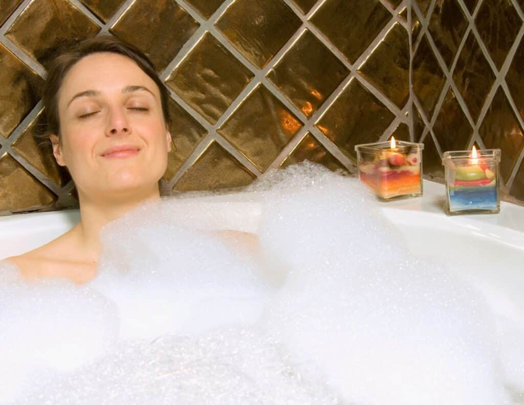 A woman has her eyes closed and  is in a bathtub with lots of bubbles  - overwhelmed moms.