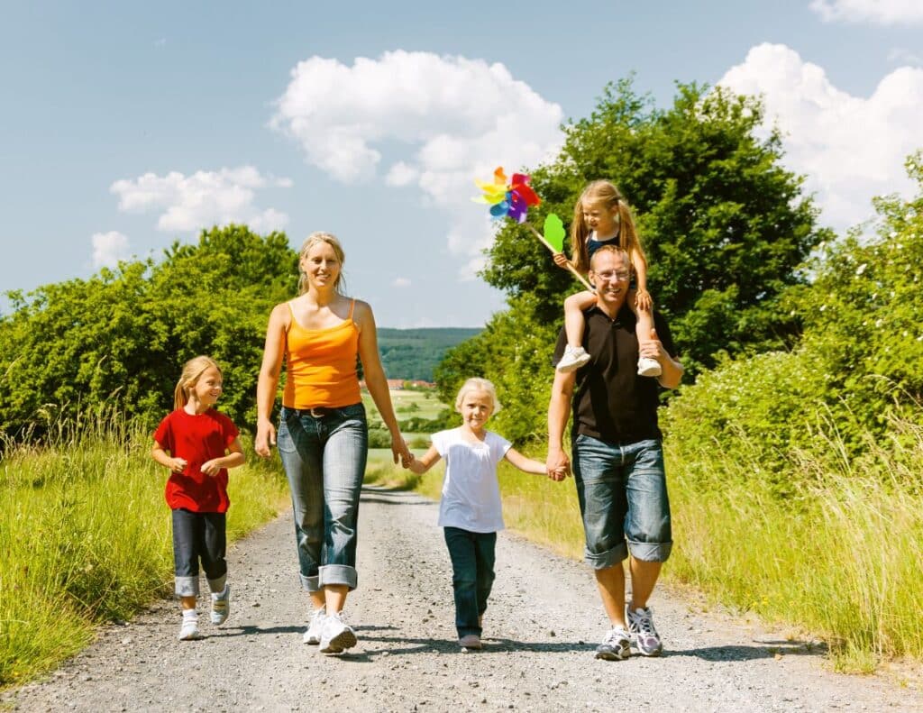 A mother, father and three children are walking down a road - cheap family activities.