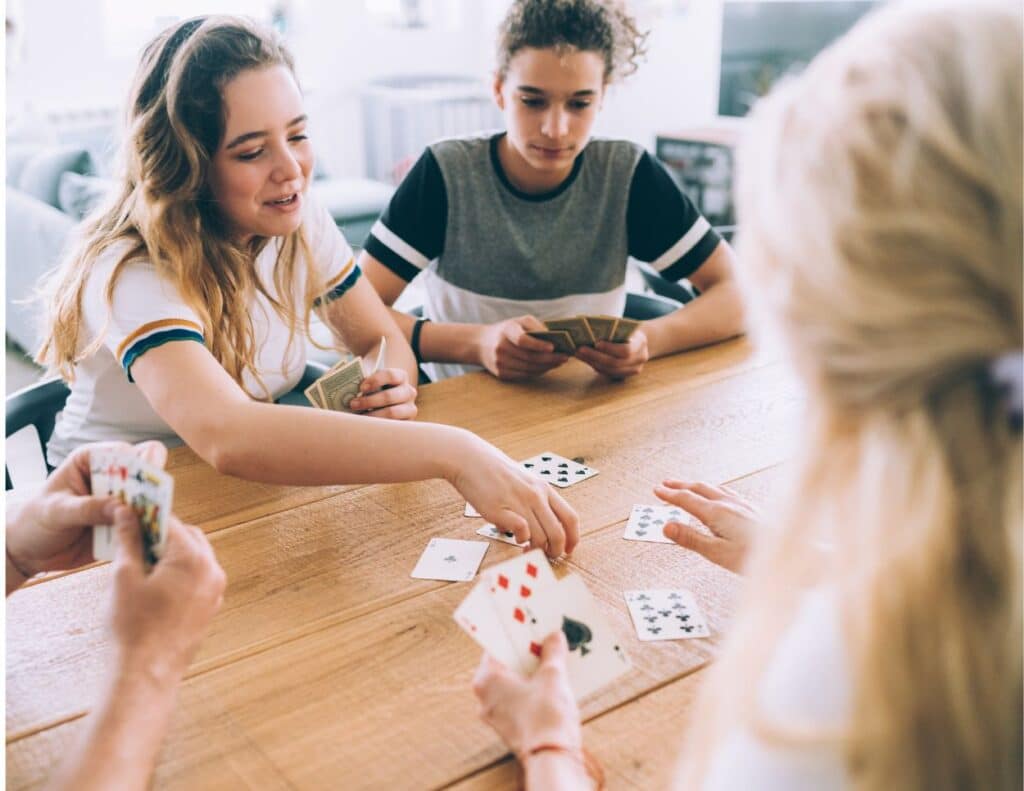 Children sitting at a table playing cards - cheap family activities.