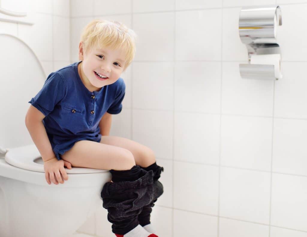 a smiling little boy sitting on a potty - weekend potty training