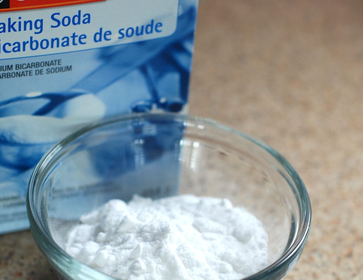 A small bowl of baking soda with a box of it next to the bowl - homemade laundry detergent.