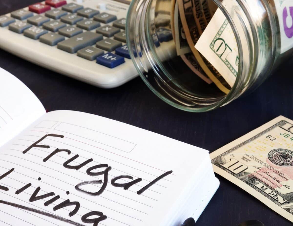 a desk with money, a calculator and a pad of paper that says, "frugal living" - how to save money on meat