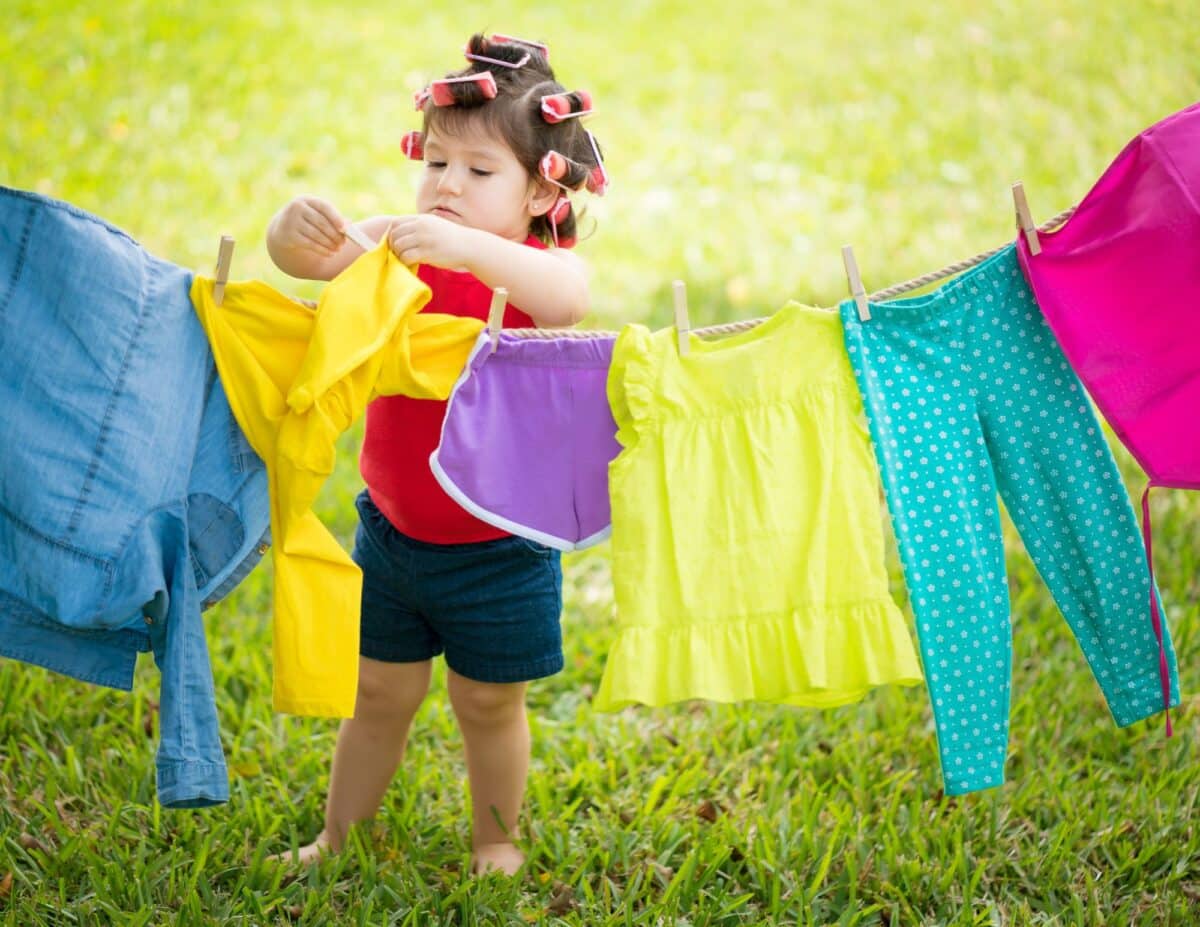 A little girl is hanging up laundry - how to save money on laundry.