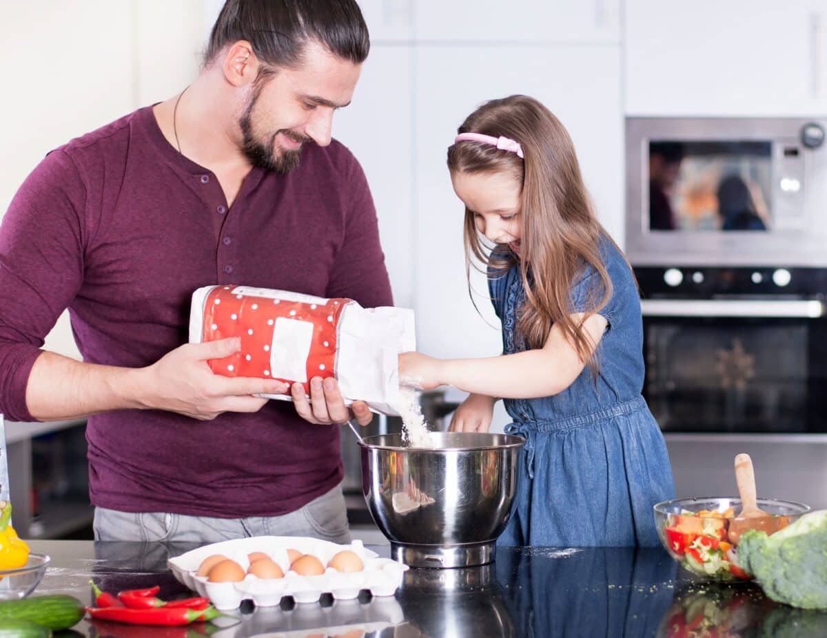 A father and daughter are cooking in the kitchen -living frugally on one income.