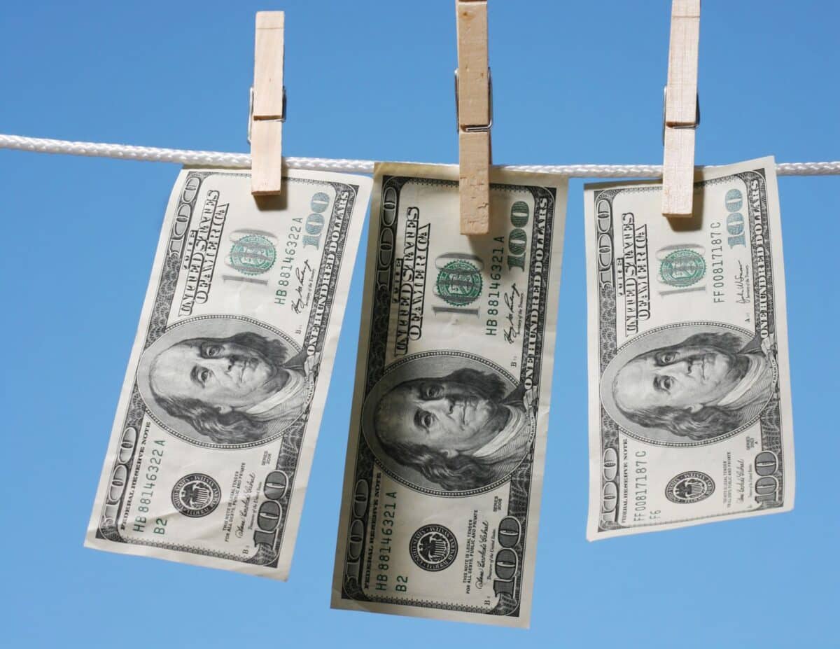 One hundred dollar bills hung on a line with clothes pins - homemade laundry detergent.