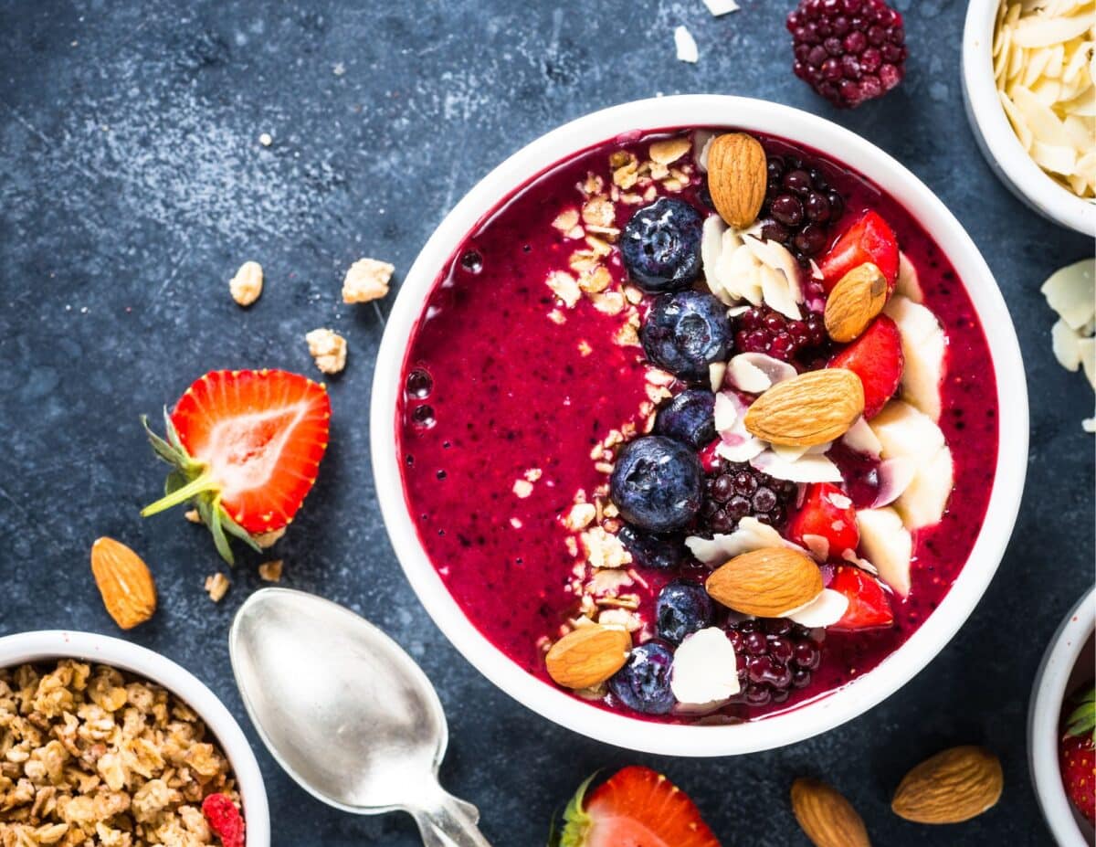 Smoothie in a bowl with fruit, nuts and oats sprinkled on top - cheap healthy snacks.

