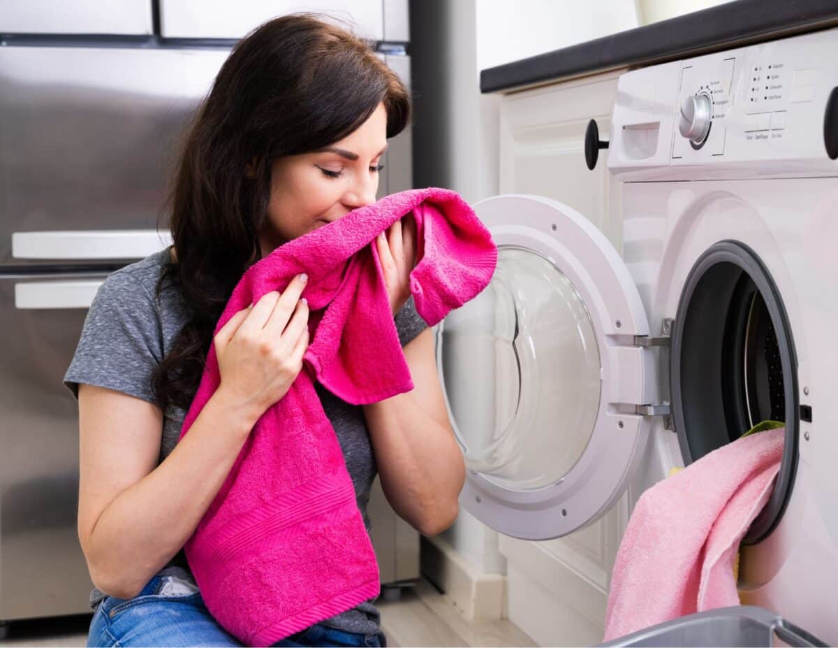 A woman is smelling a towel from the drier - homemade laundry detergent.