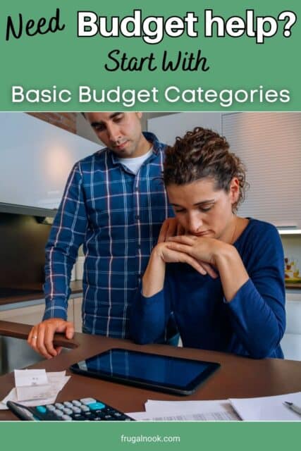 A man is standing next to a woman who is sitting at a table and they are both looking at a tablet with papers and a calculator on the table - basic budget categories