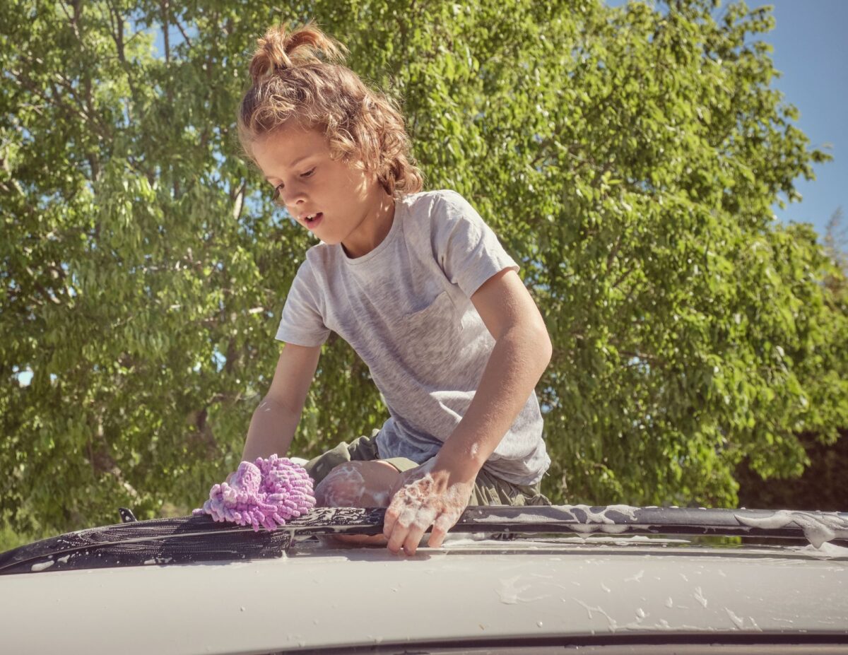 A girl is washing a car-chores for 8-year-olds.