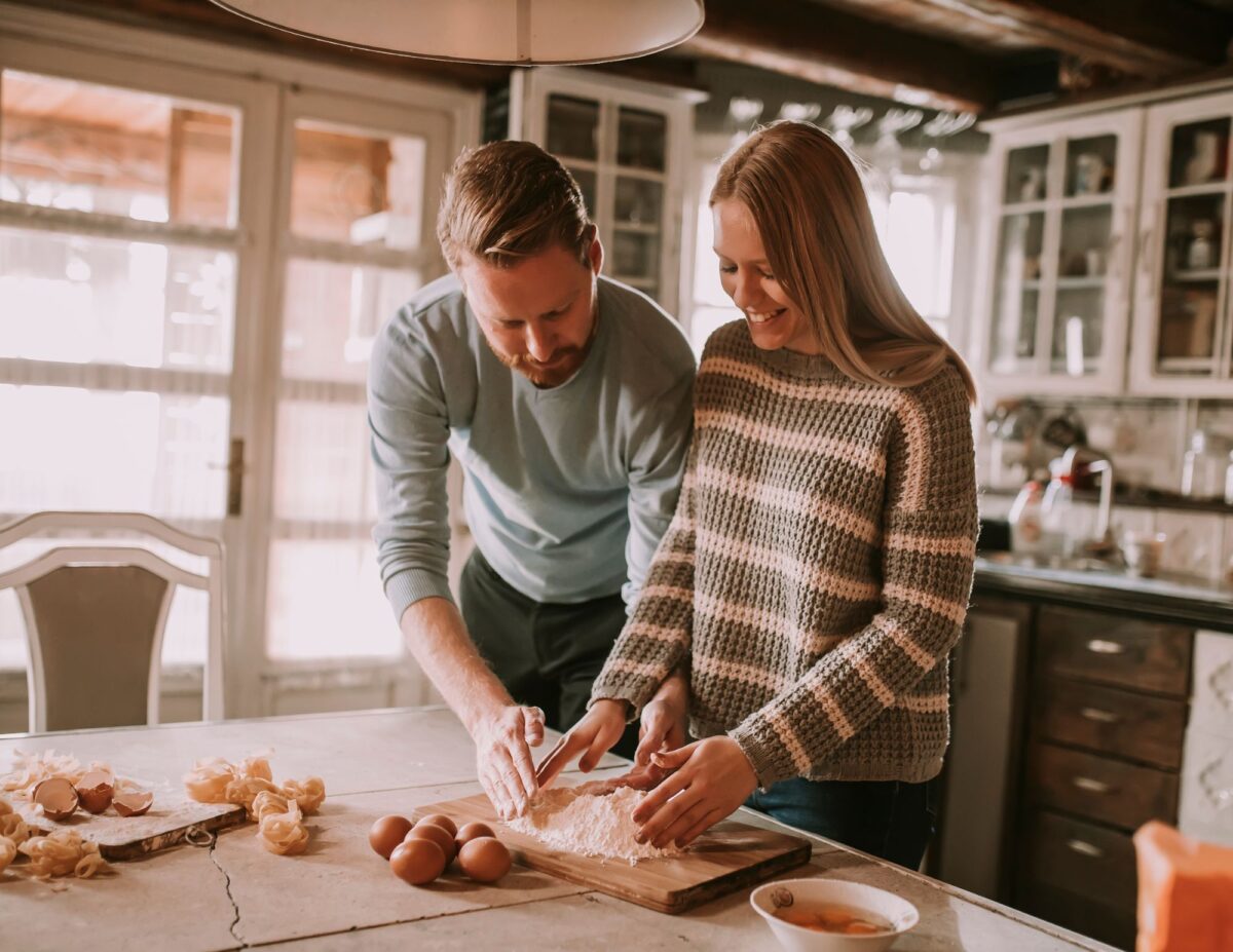 a man and woman have their hands on some flour on the table that also has some eggs - free date ideas.