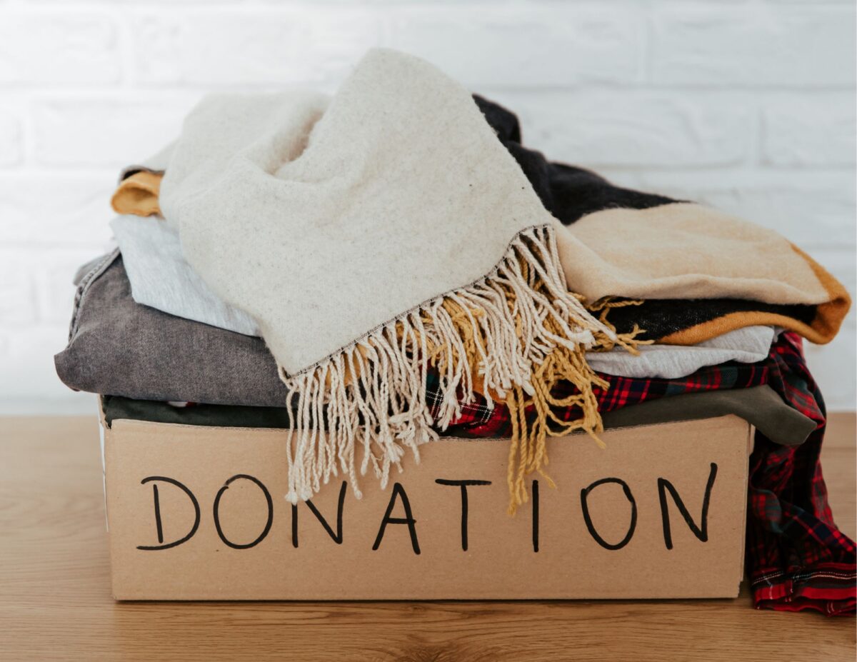 A box labeled, "donation" with a pile of clothes in it - how to declutter your home fast.