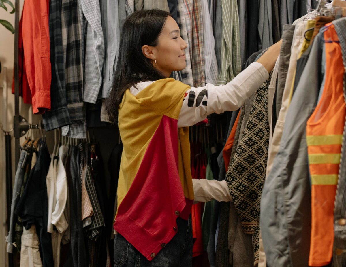 A woman is in a store looking at clothes - How to Thrift Shop Like a Pro.