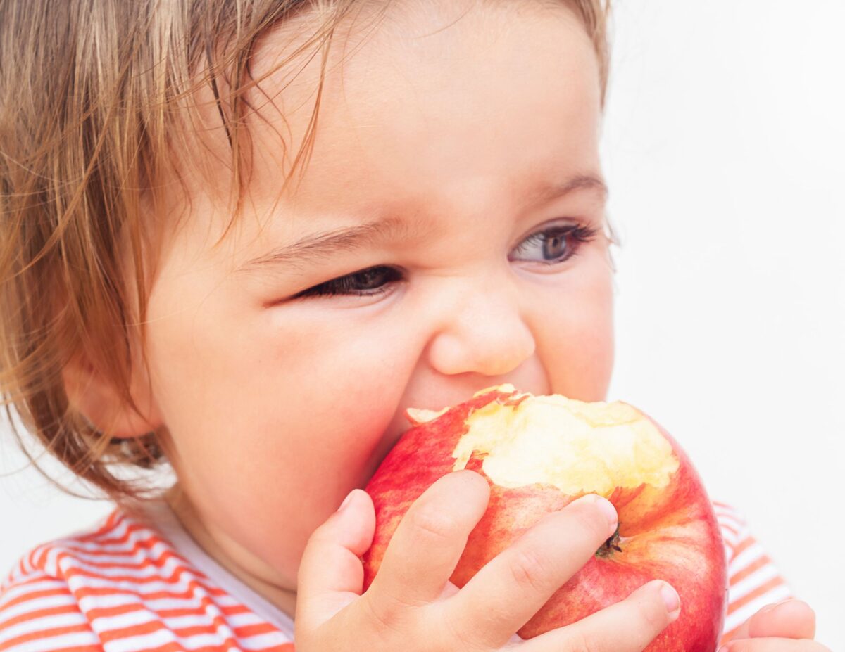 A small child is taking a bite of an apple