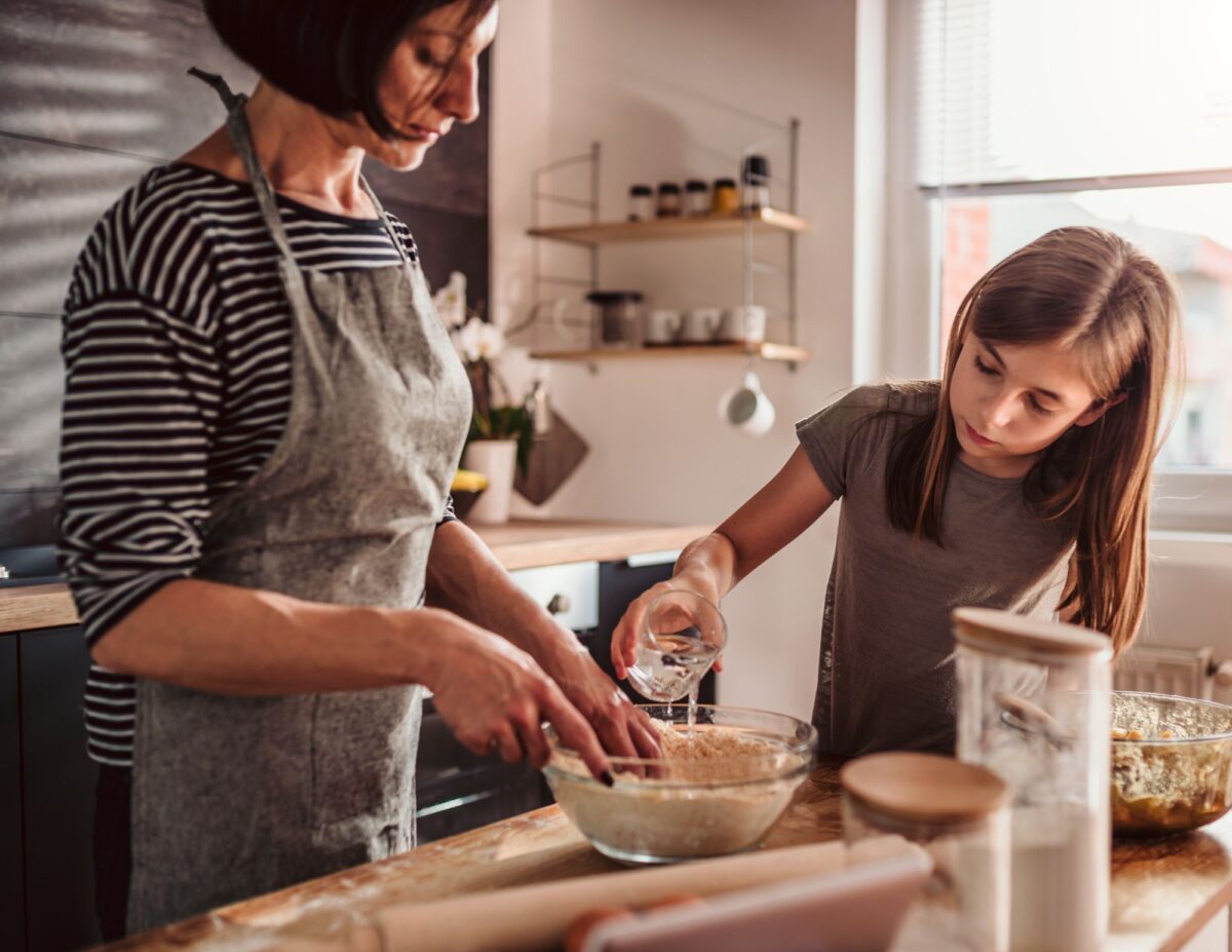 A mother and daughter are making something in the kitchen - budget-friendly fall activities.