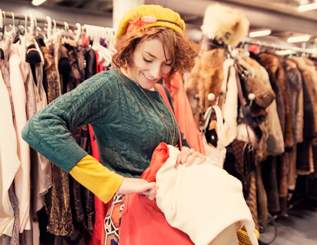 A woman is admiring some clothes she's trying on - things to stop buying to save money.
