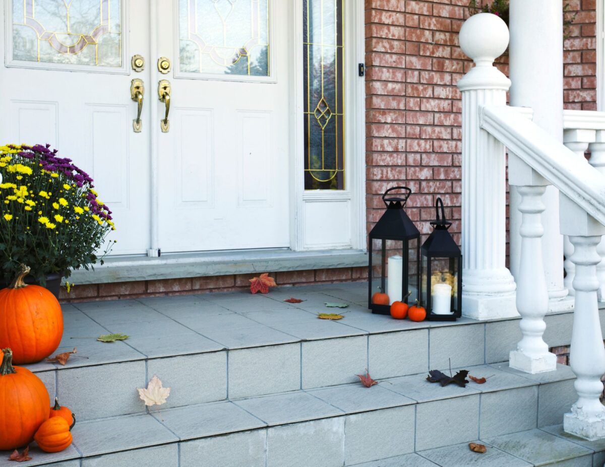 Porch with lanterns, pumpkins and fall flowers - cheap outside DIY fall decorations.