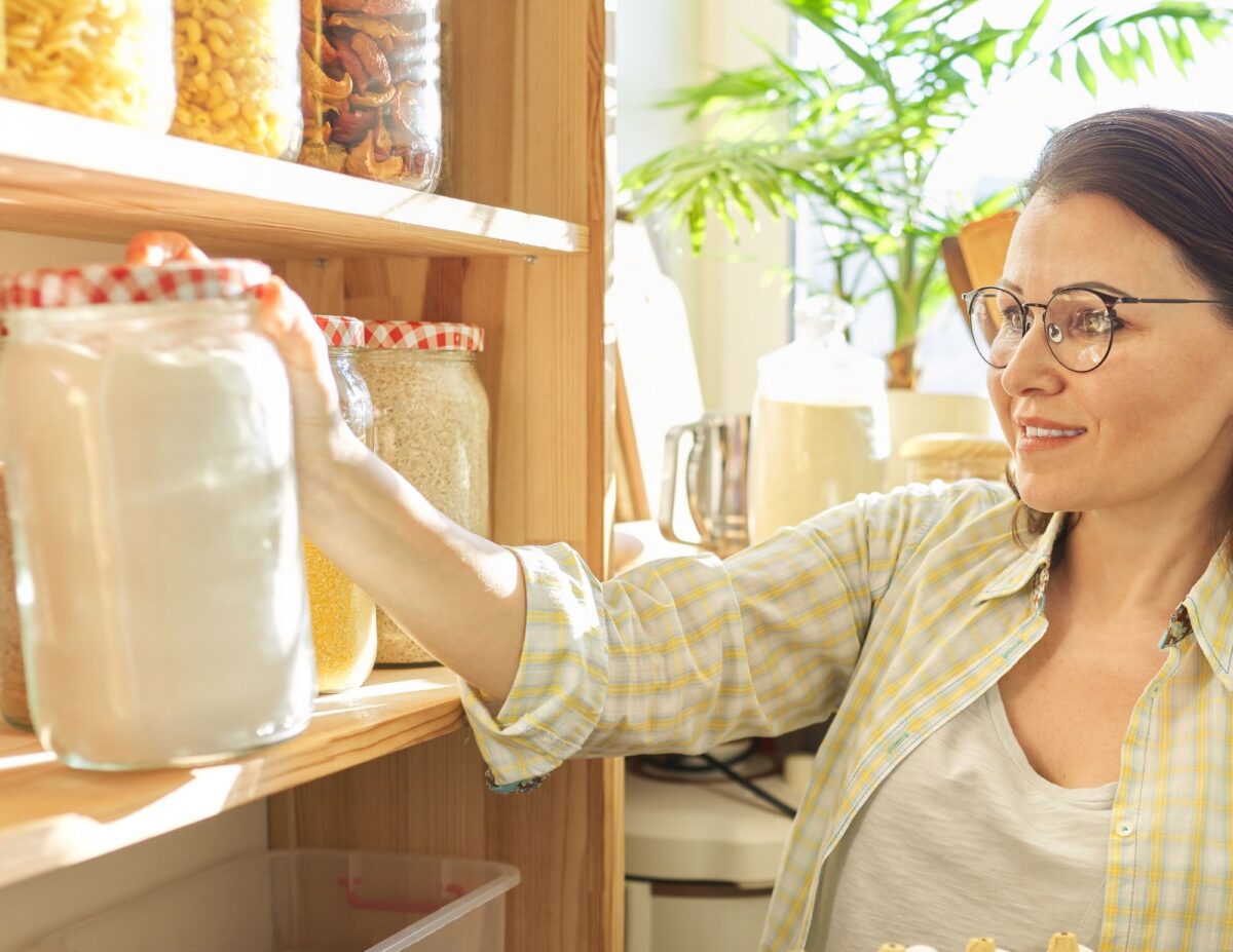 A woman is reaching for a pantry item - frugal baking tips.