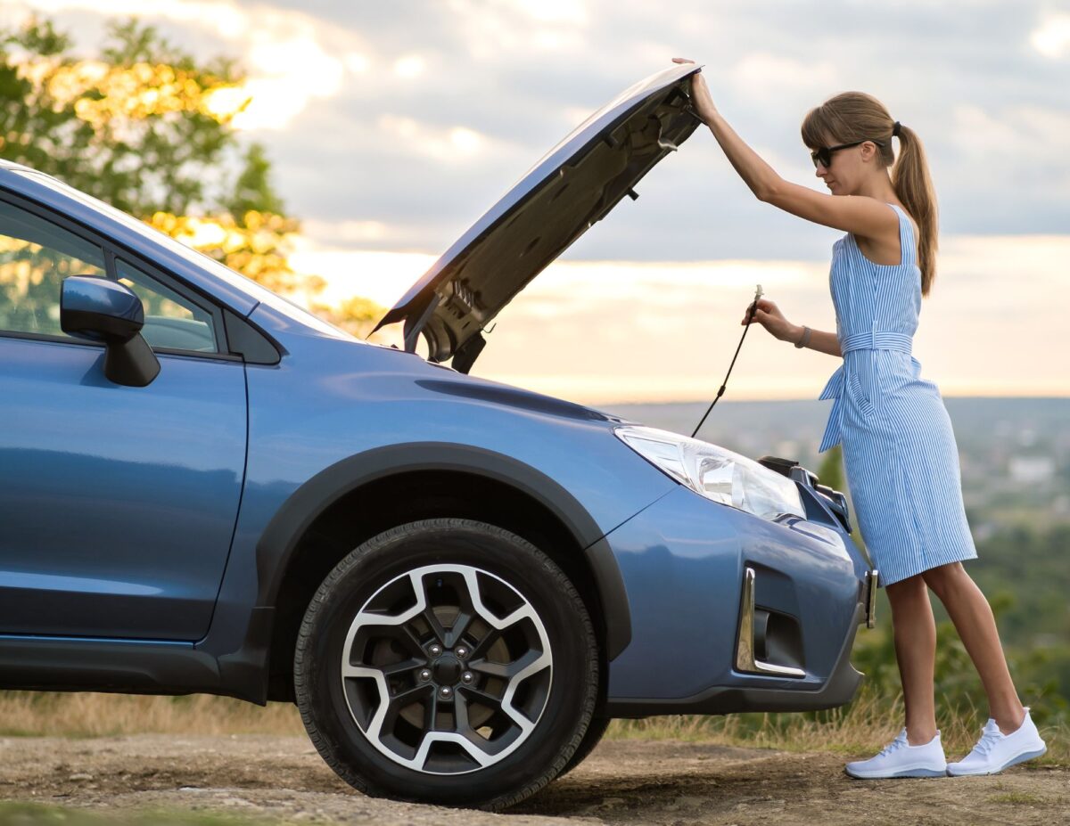 A woman is looking under the hood of her car - frugal living tips for families