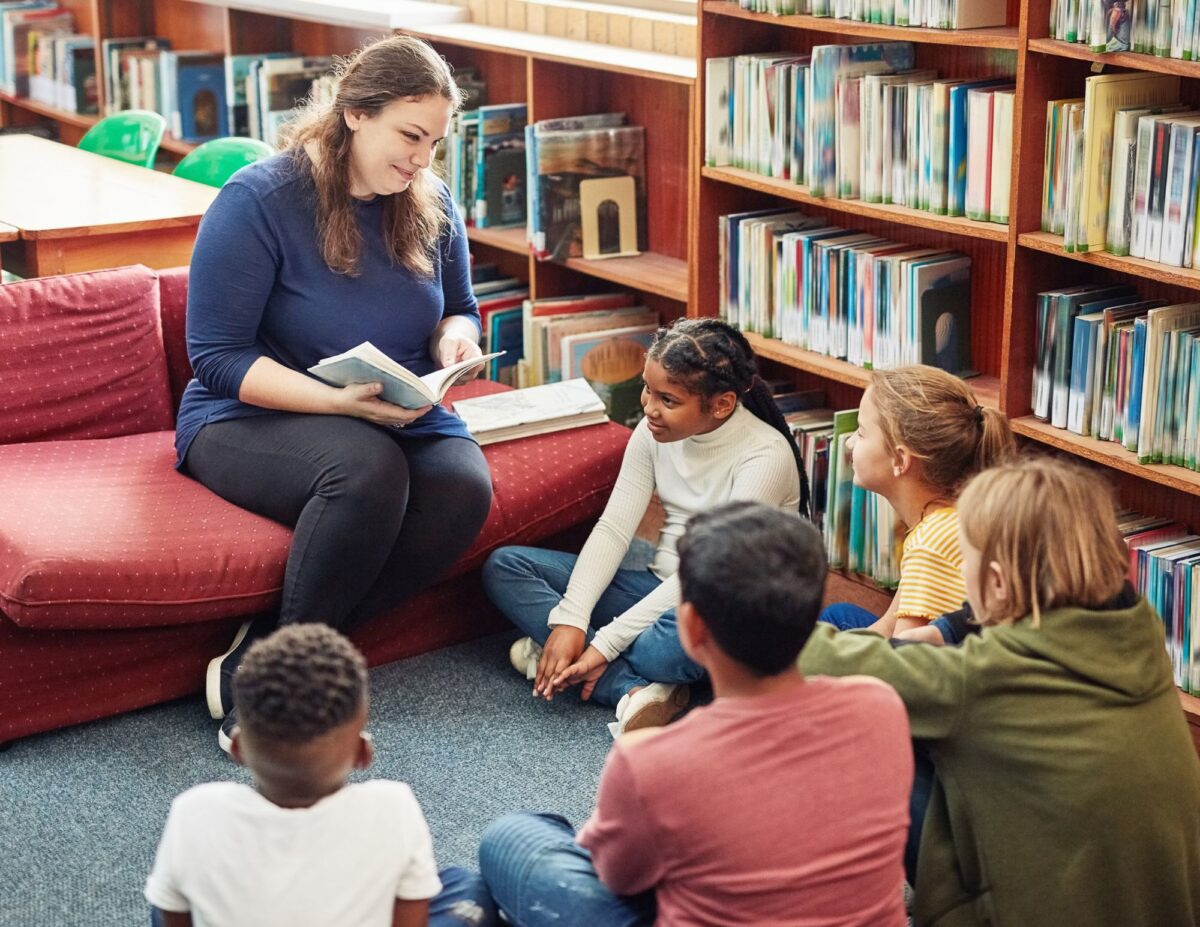 A woman is reading to children at a library - frugal living tips for families.