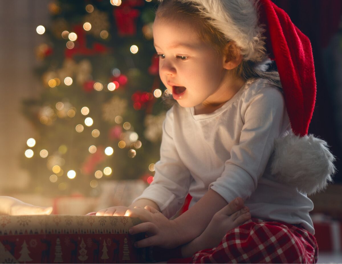 An excited child is looking at a Christmas gift.