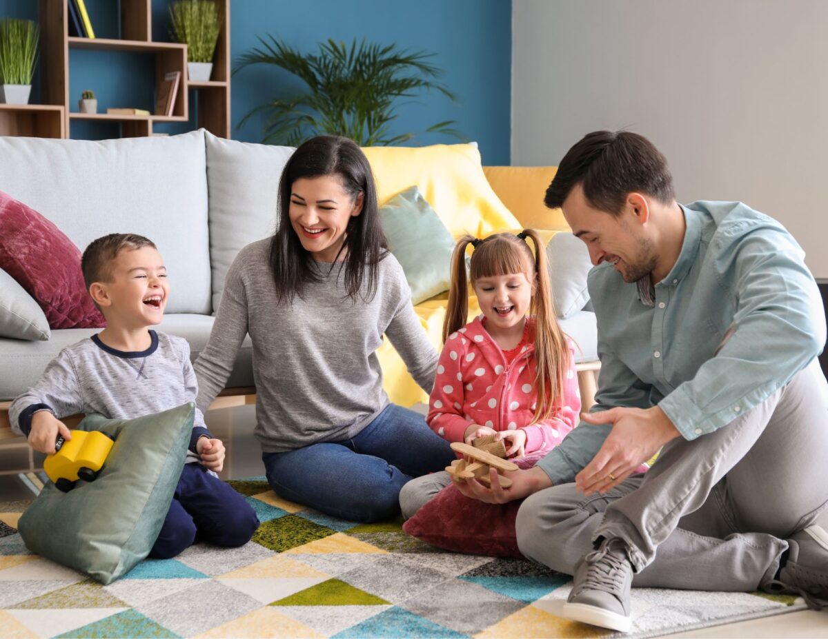 A family is sitting on the floor together talking - frugal living tips for families