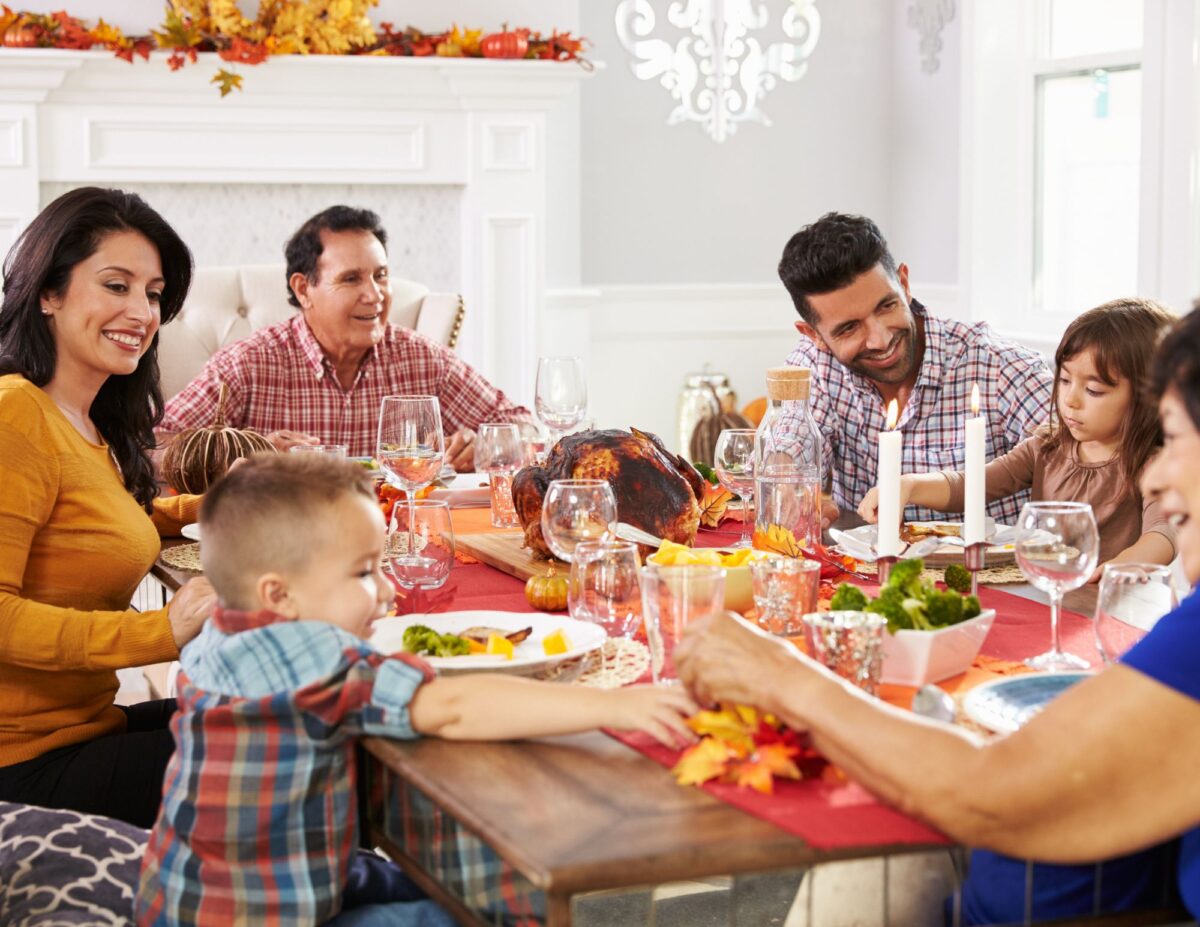 A family sitting around a dinner table - Celebrating Thanksgiving on a tight budget.