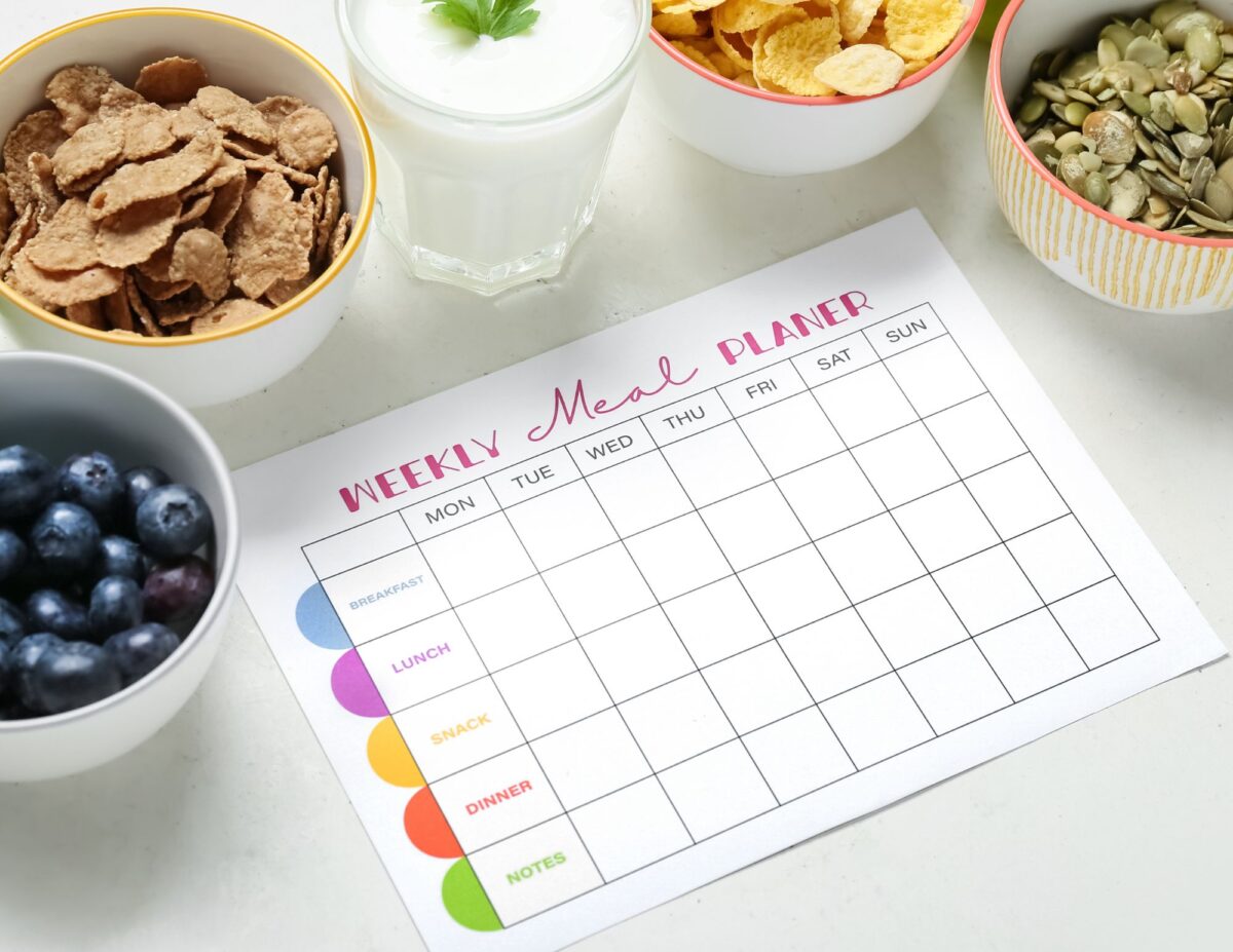 a paper that says, "weekly meal plan" is surrounded by bowls of different foods, such as blue berries, cereal and milk - frugal living tips for families.