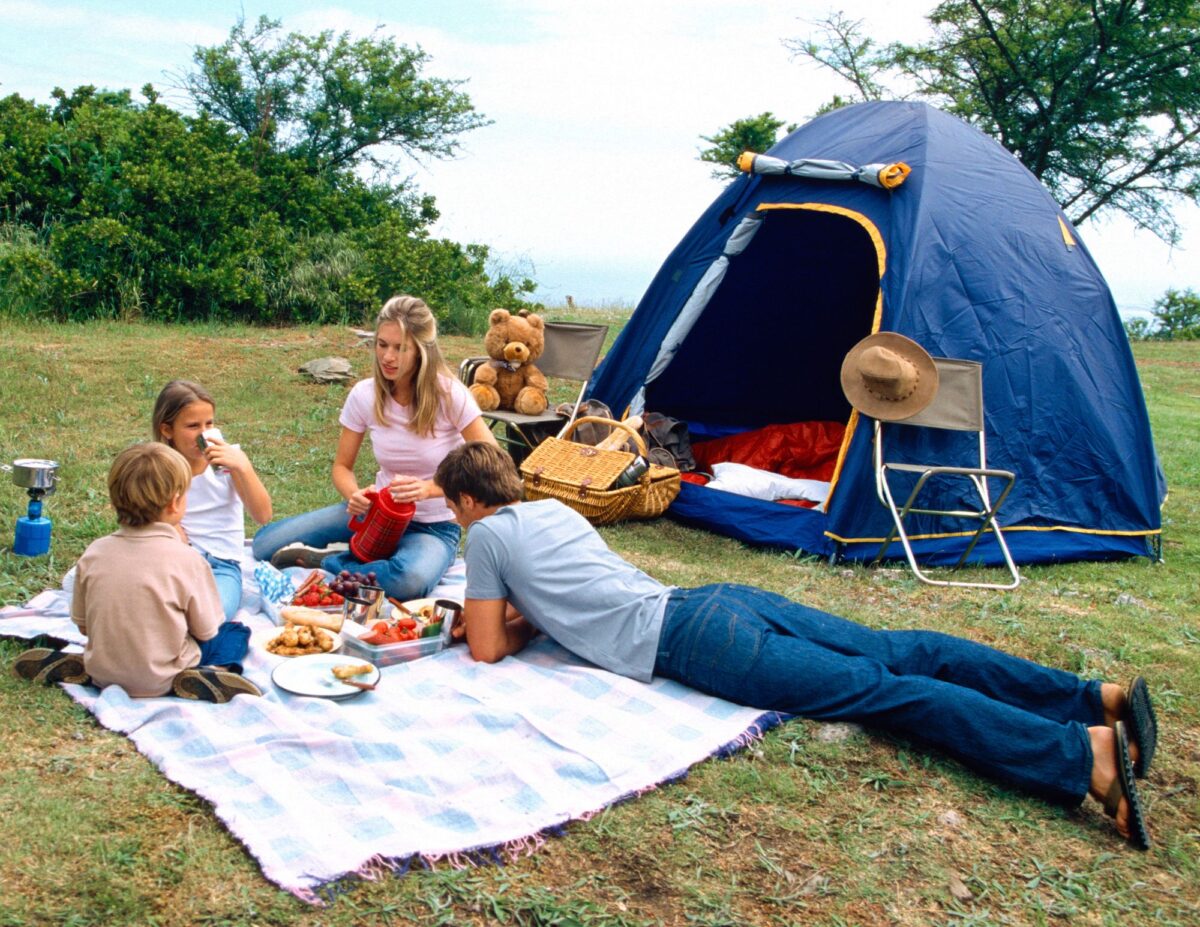 A family is camping - frugal family vacation tips.