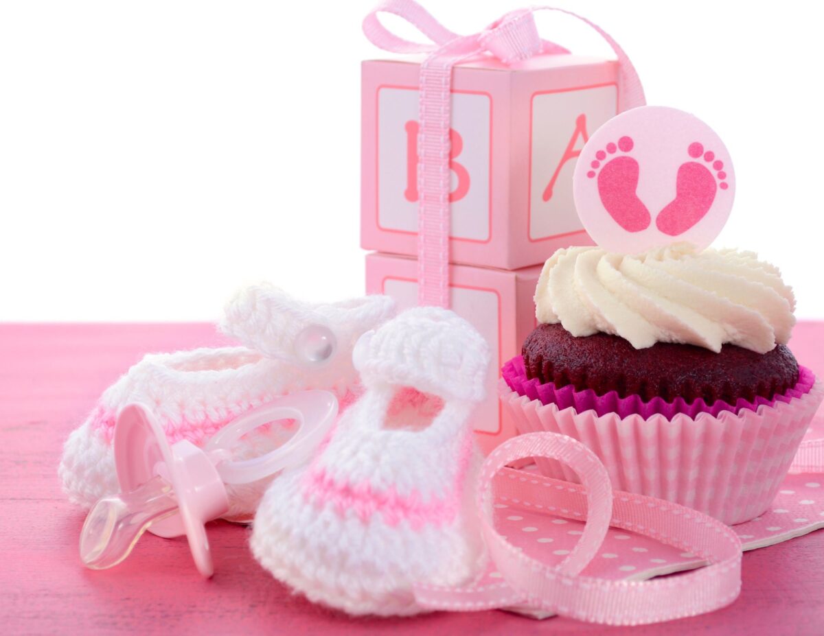 cupcake with a decoration of pink feet, a pink pacifier, and pink baby blocks - cheap baby shower food ideas.