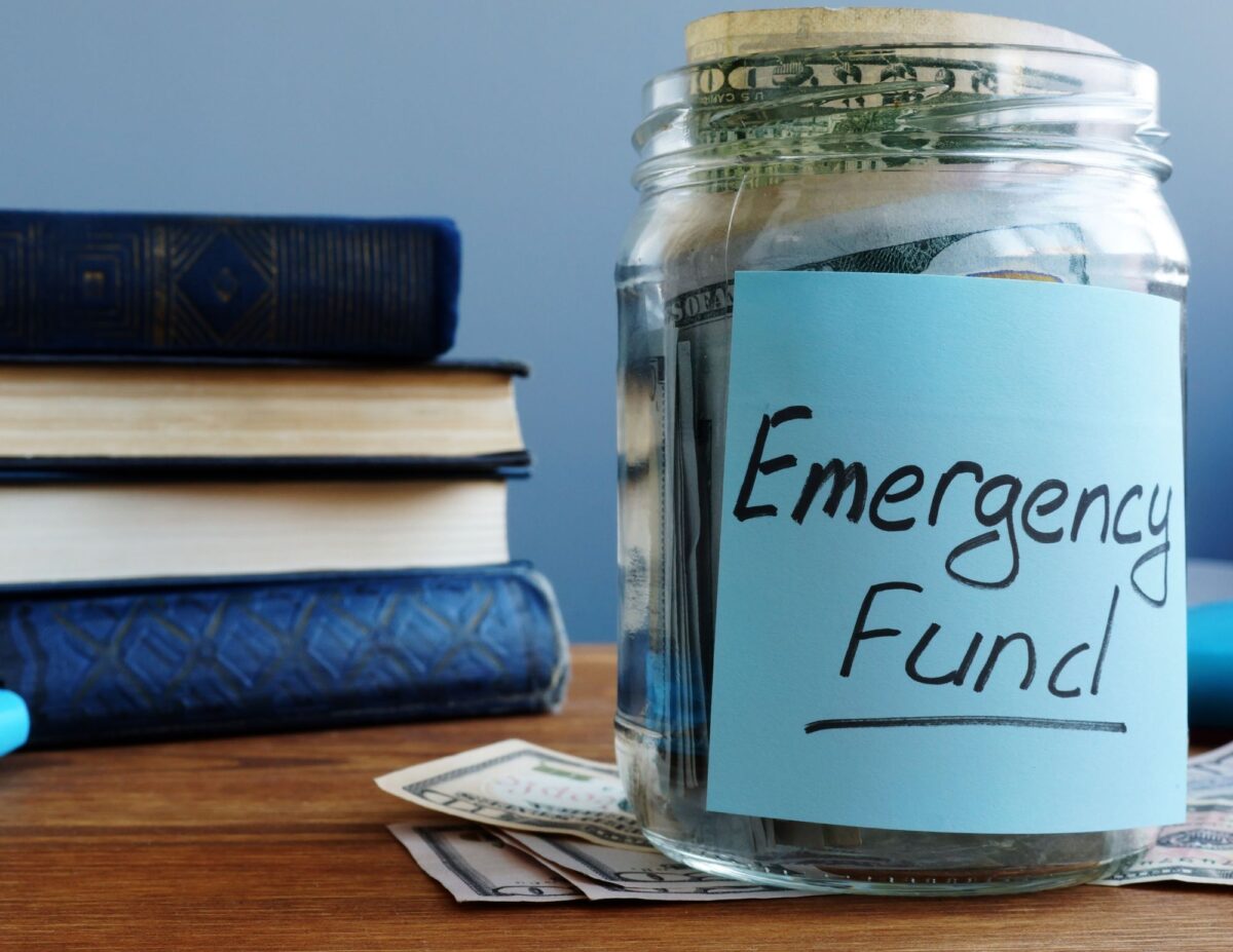 a jar with money with a sign that says, "emergency fund" - invest on a budget