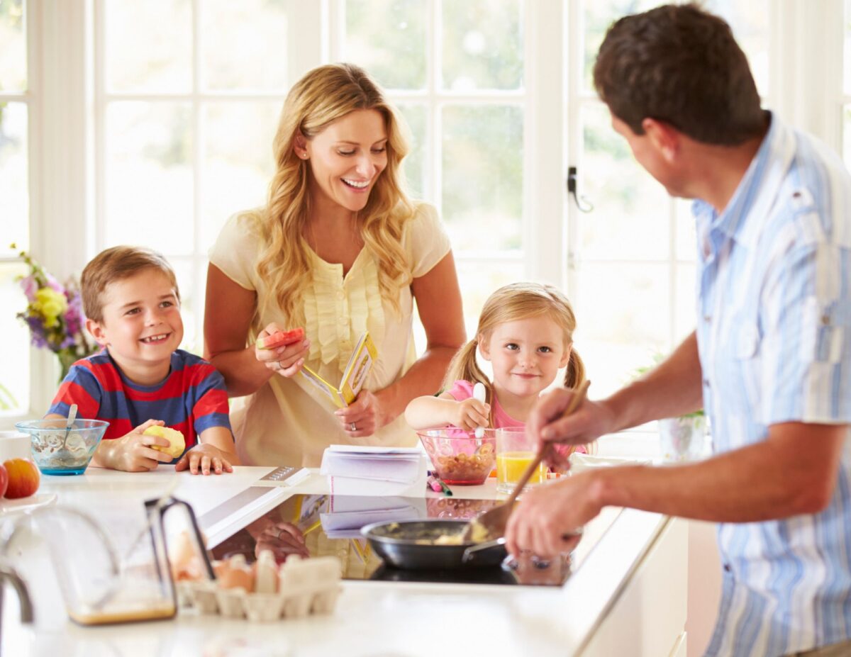 a mother, father, and two children are cooking in the kitchen - cheap winter indoor activities.