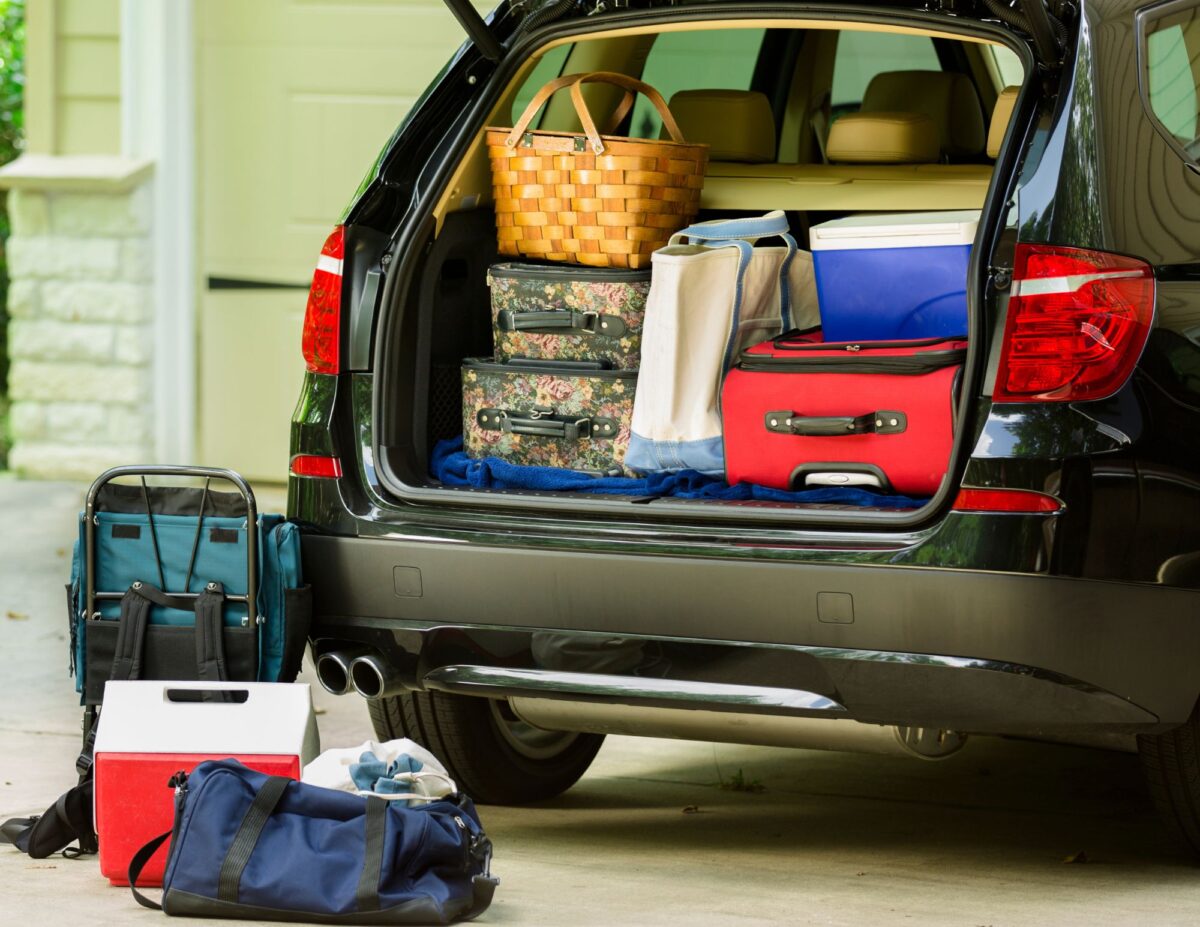 A car fully packed with luggage and picknic basket and cooler - frugal family vacation tips.