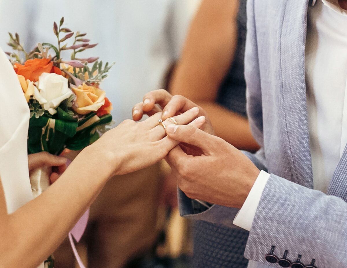 a man is putting a ring on a woman's hand - best wedding photography on a budget