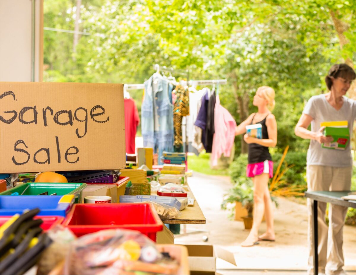 a yard sale in and out of a garage with a garage sale sign - how to have a successful yard sale