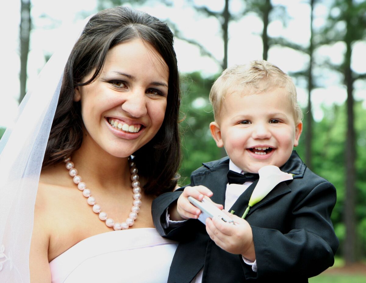 a bride is holding a little boy - best wedding photography on a budget