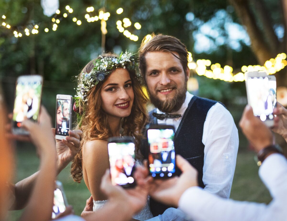 a bride and groom are having lots of people taking their picture with cell phones - outdoor wedding ideas on a budget