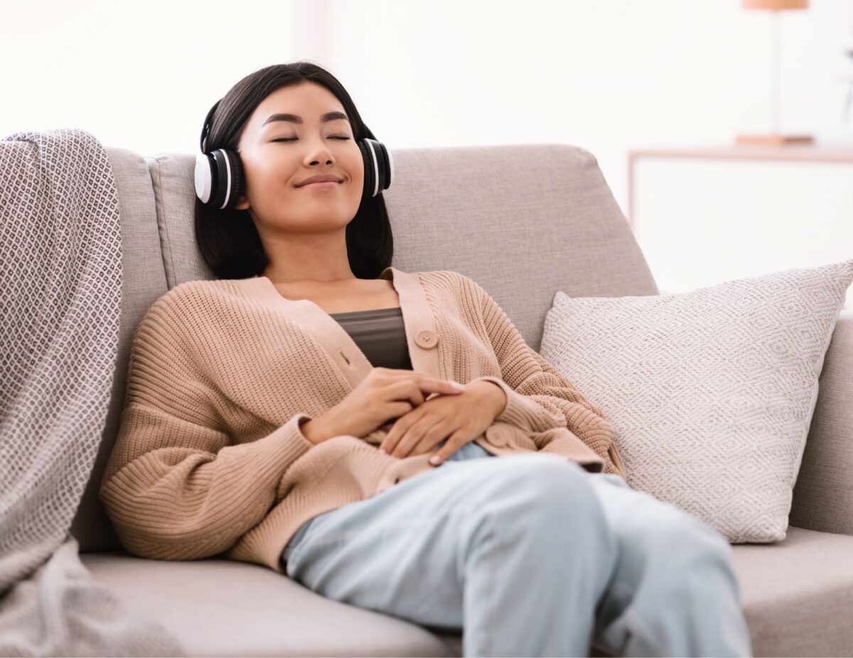 a woman has headphones on relaxing on a couch - feeling like a failure as a mom