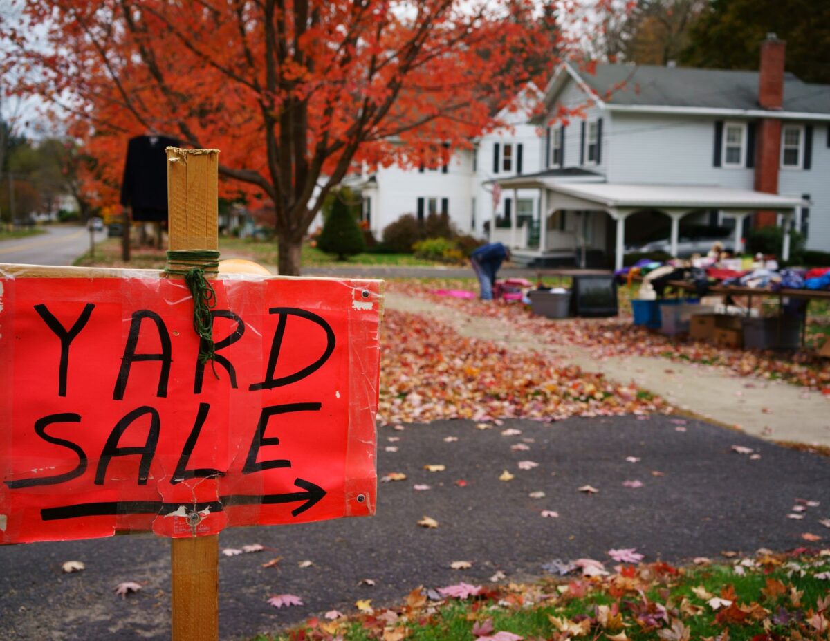 a red sign that says "yard  sale" with an arrow and a yard sale in the background - how to have a successful yard sale