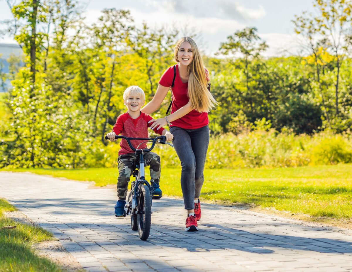 a woman is helping a boy ride a bike - benefits of being a stay at home mom