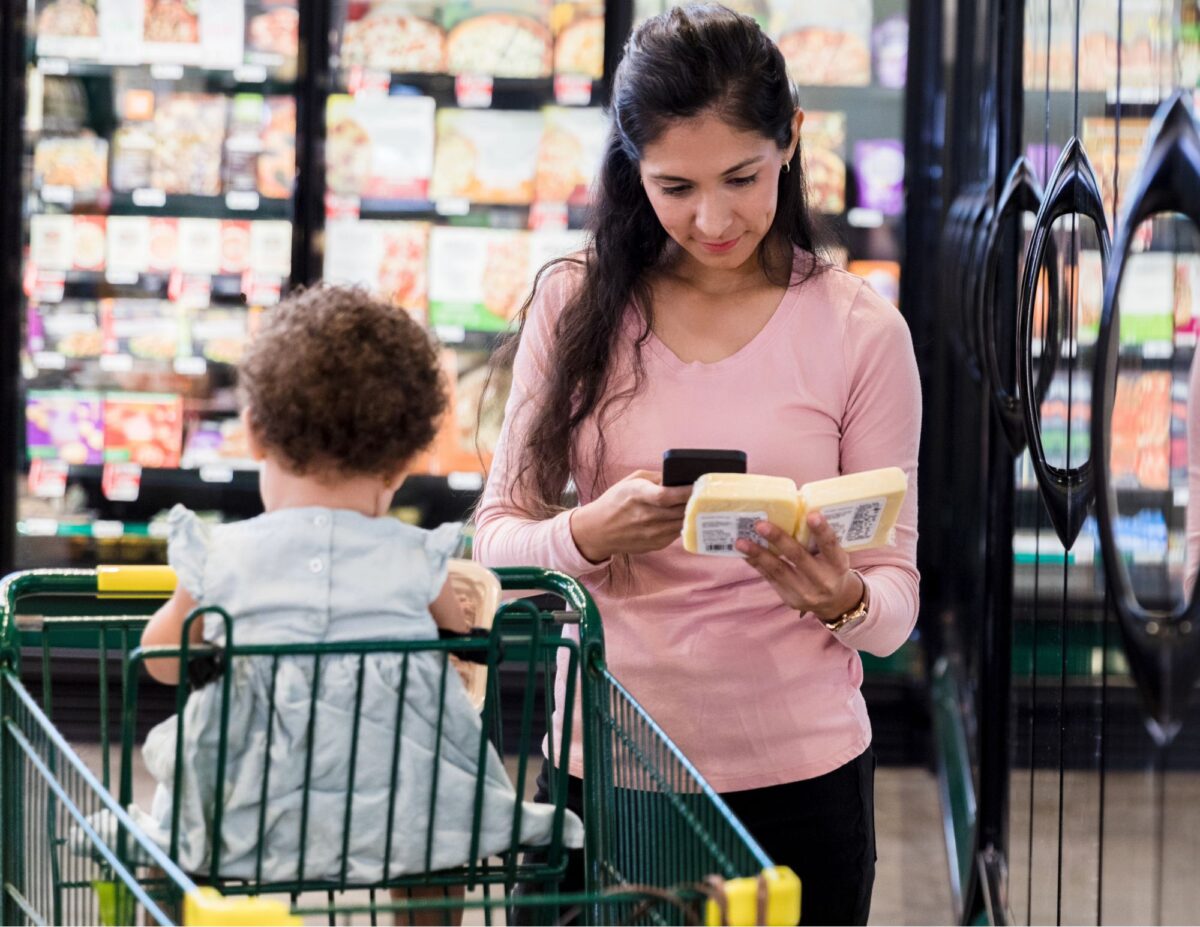 A woman is comparing groceries at the store - how to save money on groceries without coupons