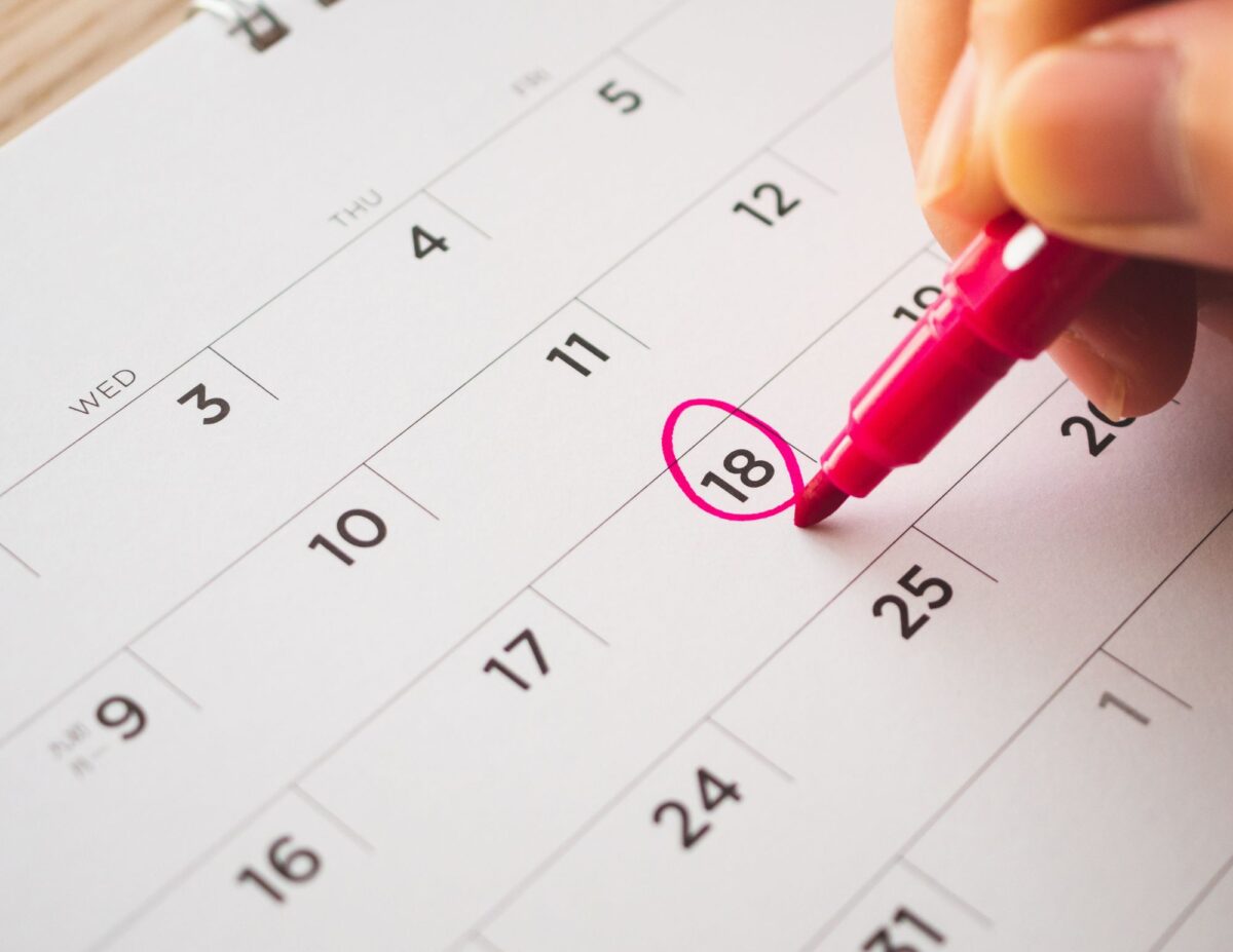 someone circling a date on a calendar - 52-week money savings challenge