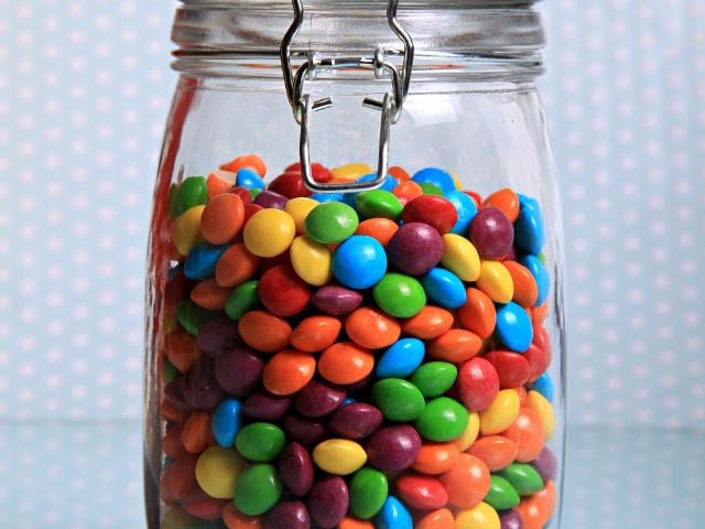 a mason jar filled with colored candy - baby shower favors
