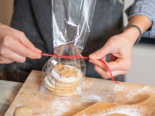 someone putting a ribbon on cookies in a bag - baby shower favors