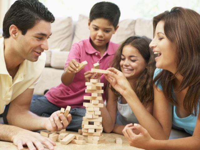 a man, woman and 2 children are playing a game - family traditions