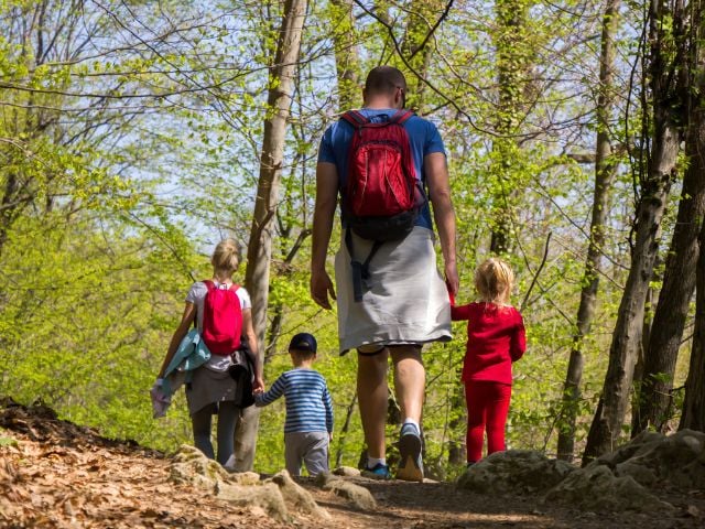 a man, woman and two children are hiking - family traditions
