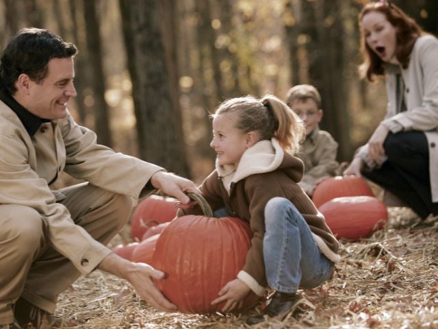 a man woman and child are pumpkin picking - family traditions